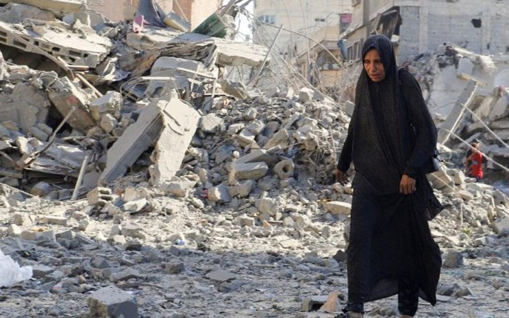 Donna palestinese cammina tra le macerie dopo un bombardamento a Gaza